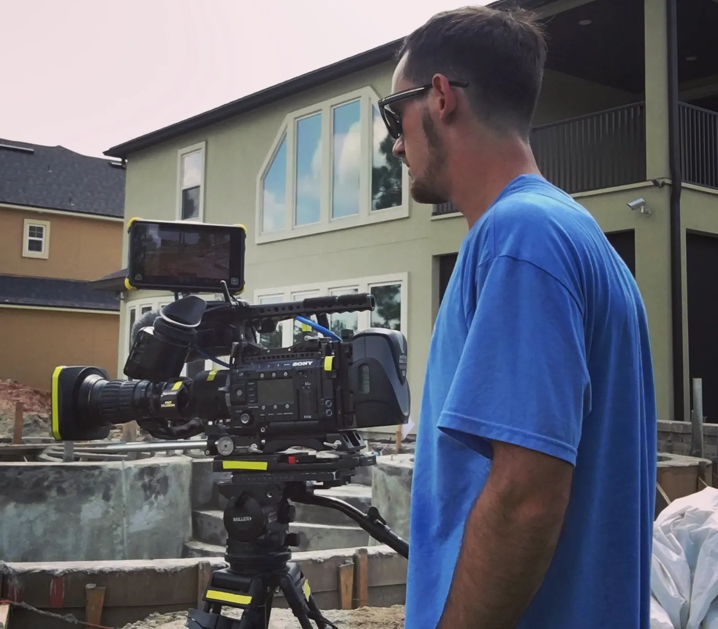 Ryan beside a Sony cinema camera on a tripod at a backyard construction site